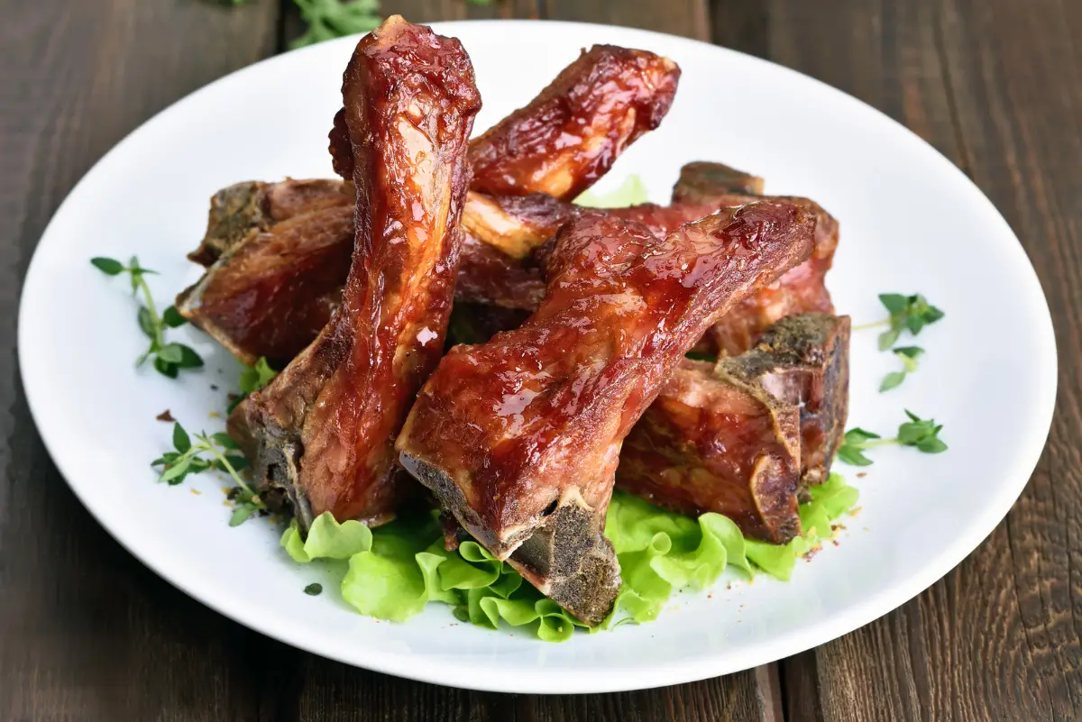 Melt in Your Mouth Barbecue Pork Ribs on a bed of lettuce, on a white plate.