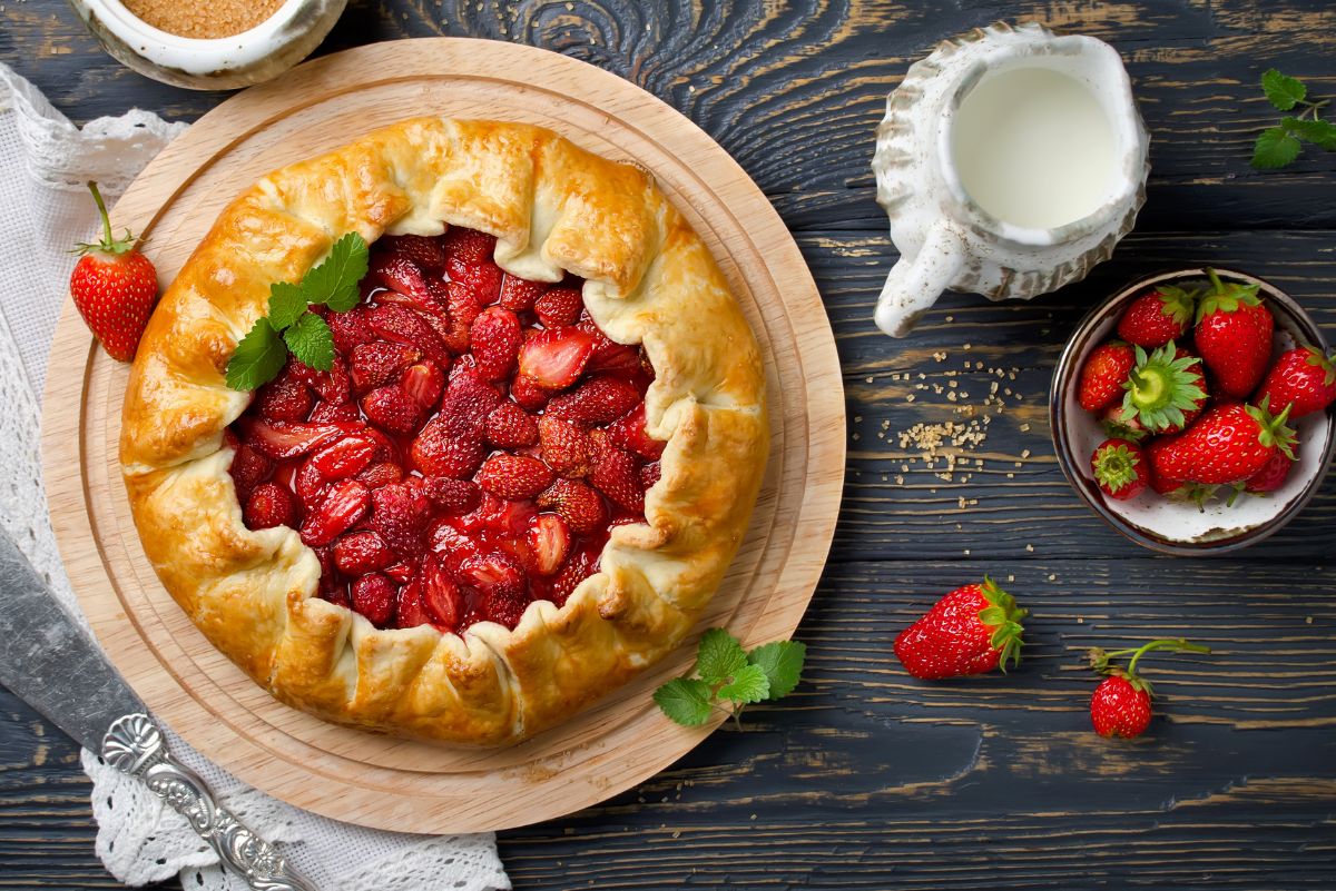 Simple and Delicious Strawberry Galette on a dark, slate surface. Fresh strawberries around it.