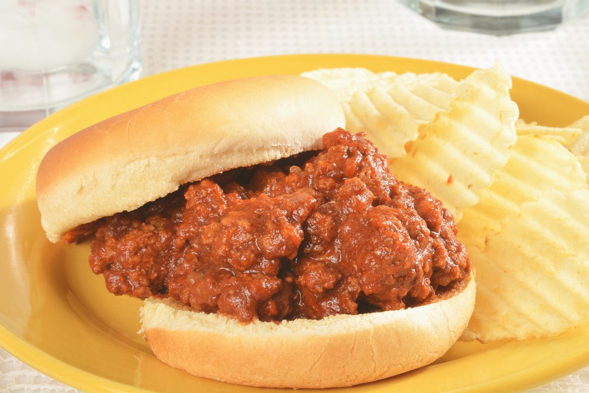 Copycat Manwich Sloppy Joe's on a yellow plate with potato chips.