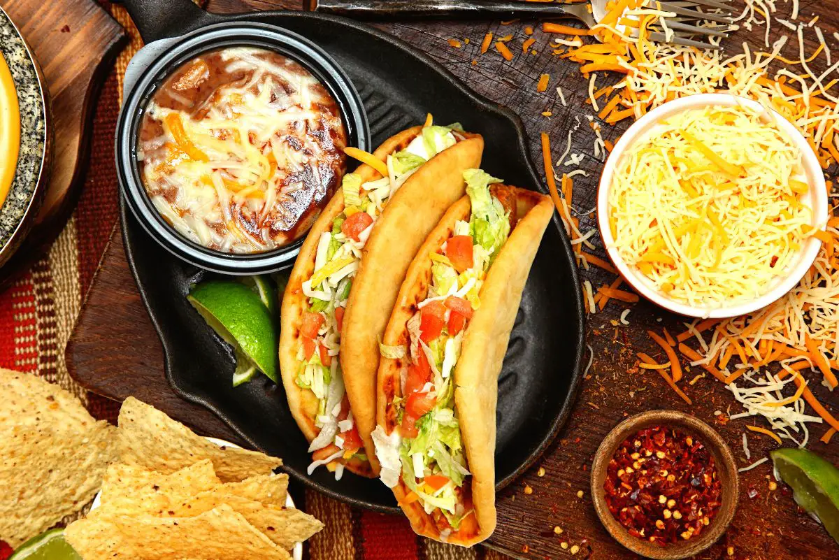 overhead view of 2 Copycat Taco Bell Chalupas on a black plate surrounded by ingredients.