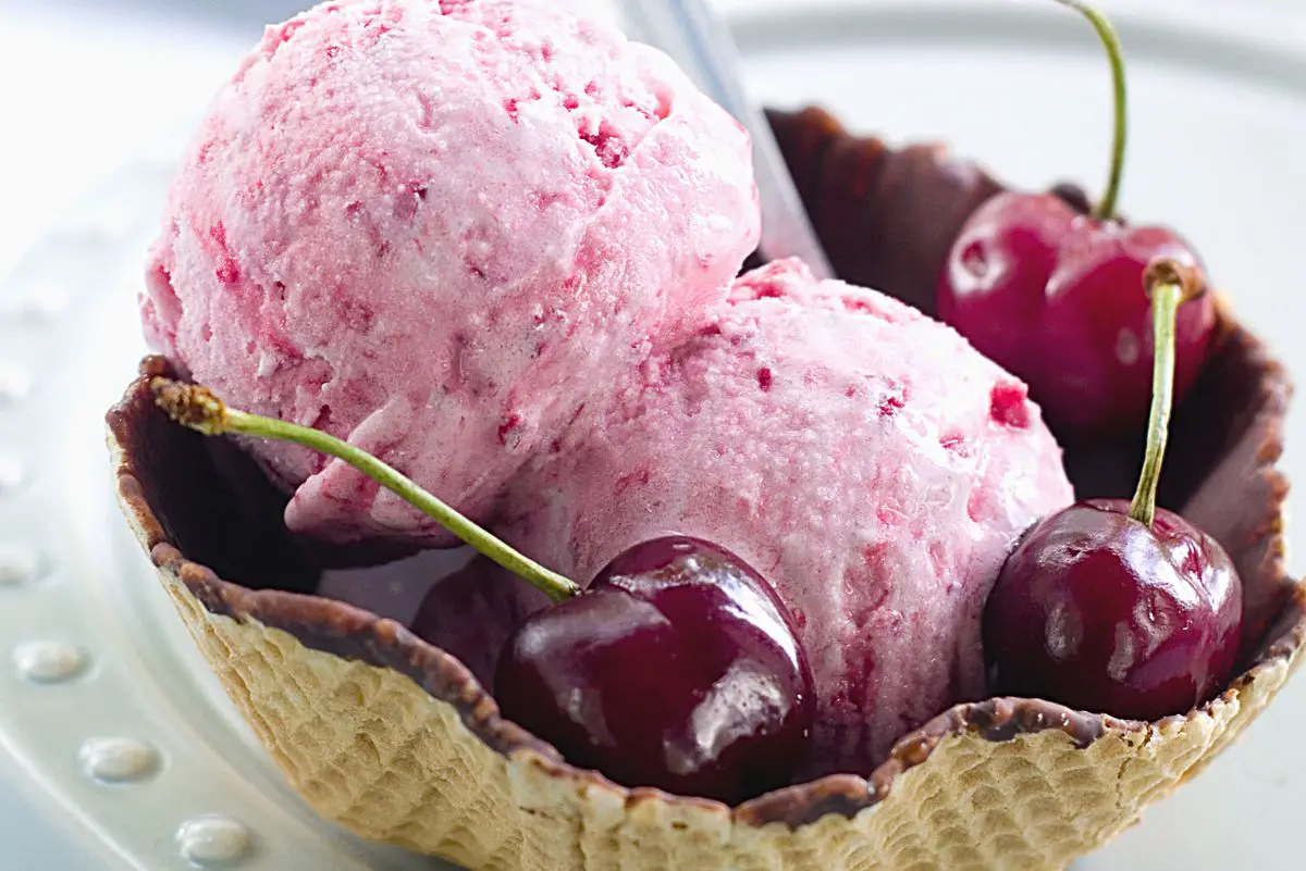 Closeup of Homemade Cherry Ice Cream in a chocolate covered waffle bowl with fresh cherries.