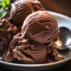 A bowl filled with scoops of chocolate custard ice cream.