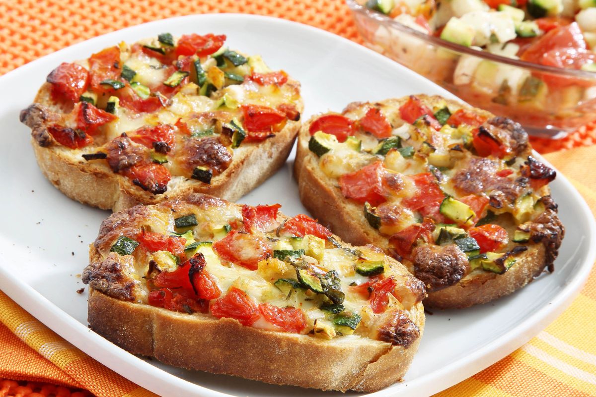 3 Quick and Easy Italian Bruschetta on a white plate with a clear bowl filled with salsa behind it.