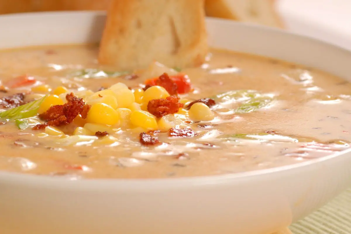 Easy Homemade Corn Chowder in a white bowl with a slice of bread.