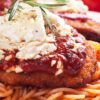 This is a close-up photograph highlighting the textures and colors of the Simple Italian Chicken Parmesan dish. A golden-brown breaded chicken breast, smothered in a rich red marinara sauce and topped with a generous portion of crumbled white Monterey Jack cheese, sits atop a twist of al dente spaghetti. The dish is garnished with a sprig of fresh rosemary, adding a pop of green against the warm tones of the chicken and pasta.