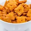 Close-up of a white bowl filled with homemade copycat Cheez-It crackers. The golden orange cheddar squares are baked crisp, topped with coarse salt, and show small center holes, capturing the classic cheesy, crunchy snack look.