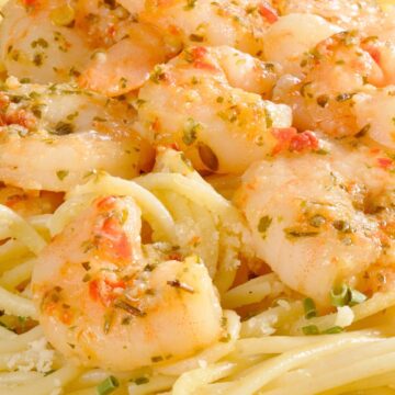 Close-up of shrimp scampi over spaghetti with garlic butter sauce, herbs, and red pepper flakes. Tender shrimp coated in a light lemon garlic sauce served on pasta with grated Parmesan. High protein shrimp scampi recipe, easy seafood pasta dinner.