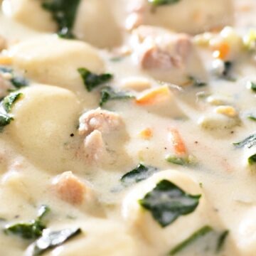 Creamy chicken gnocchi soup with tender potato gnocchi, chunks of chicken, carrots, and fresh spinach in a rich white broth. Close-up of a hearty Italian-style soup similar to Olive Garden Chicken Gnocchi Soup, thick and velvety with visible herbs and vegetables in a white bowl.