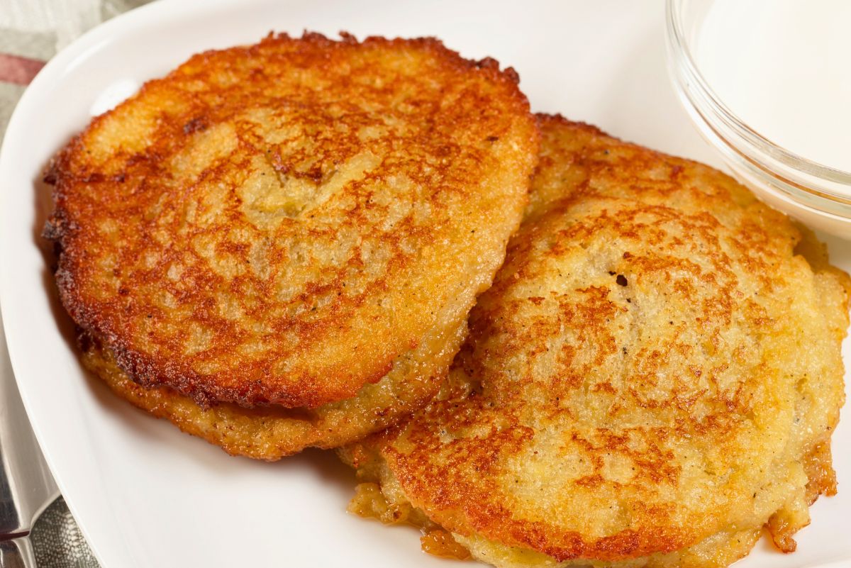 Three golden brown skillet mashed potato cakes on a white plate, crispy outside and tender inside, with a small bowl of creamy dipping sauce on the side. Pan fried potato patties made from leftover mashed potatoes, easy comfort food side dish or quick snack.