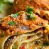 Close-up of vegetarian lasagna roll ups filled with mushrooms, spinach, zucchini, and red bell pepper, topped with rich marinara sauce, melted cheese, and fresh parsley. Creamy ricotta-style filling wrapped in tender pasta sheets on a white plate. High protein meatless Italian dinner recipe.